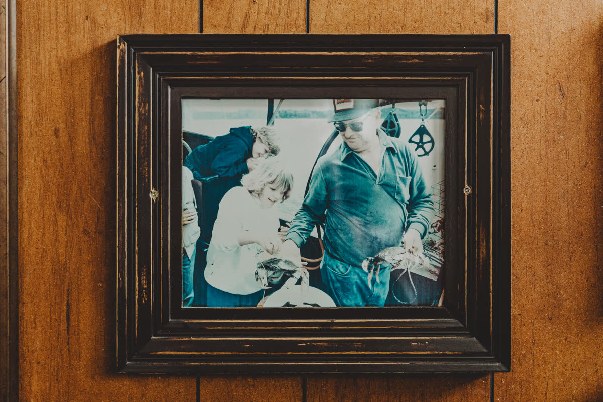Framed vintage photo of a Newport crab fishing crew on the wood-paneled wall of the Barge Inn Tavern