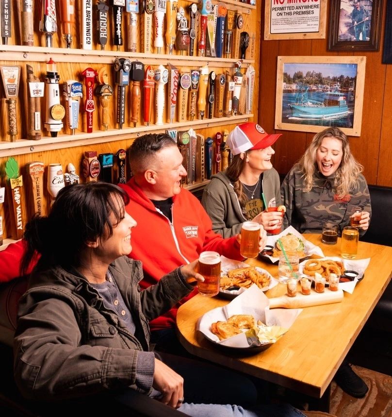 Friends laughing in a booth at Barge Inn Tavern Newport Oregon